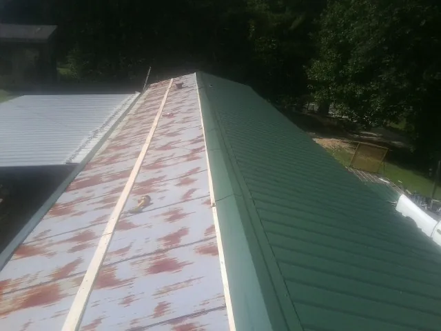 Old rusted panels beside newly installed green metal roofing — Wind Damage Roof Repair by Roofing Brothers in South Houston
