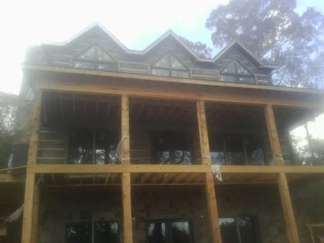 Dormers and porch framing on a large log home under construction — Roof Coating work by our crew in South Houston