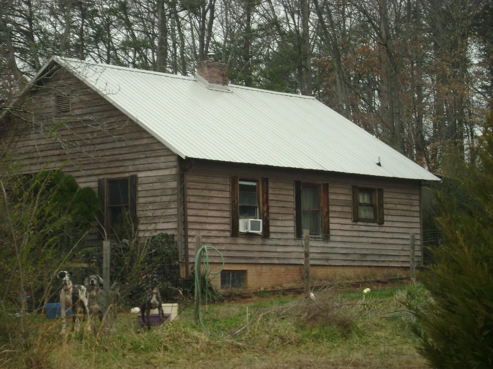 White metal roof on an old wood sided farmhouse, from a Asphalt Shingle Roof Repair job in South Houston