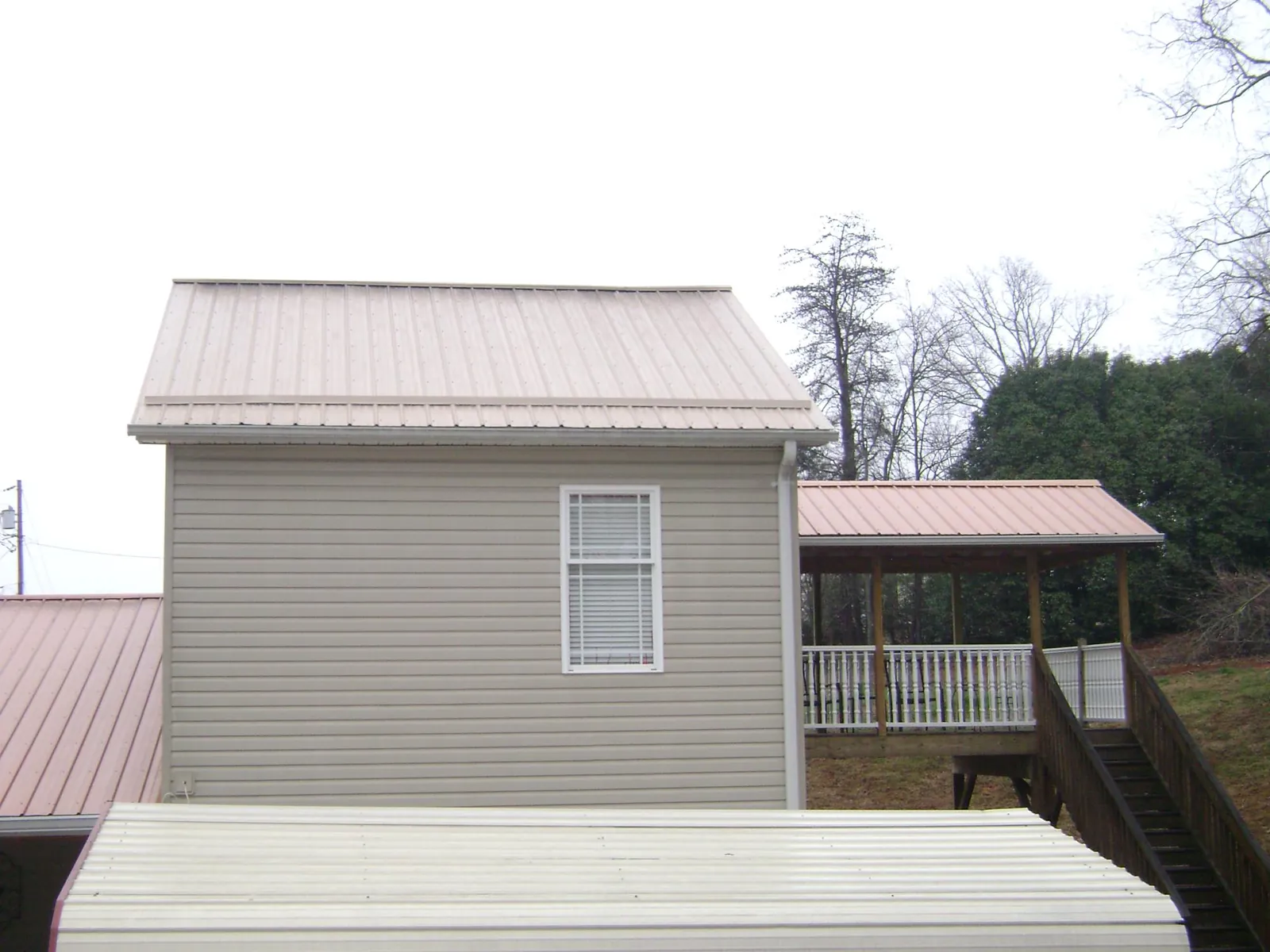 Tan metal roofs on a two story addition and attached porch, from a Roof Replacement job in South Houston