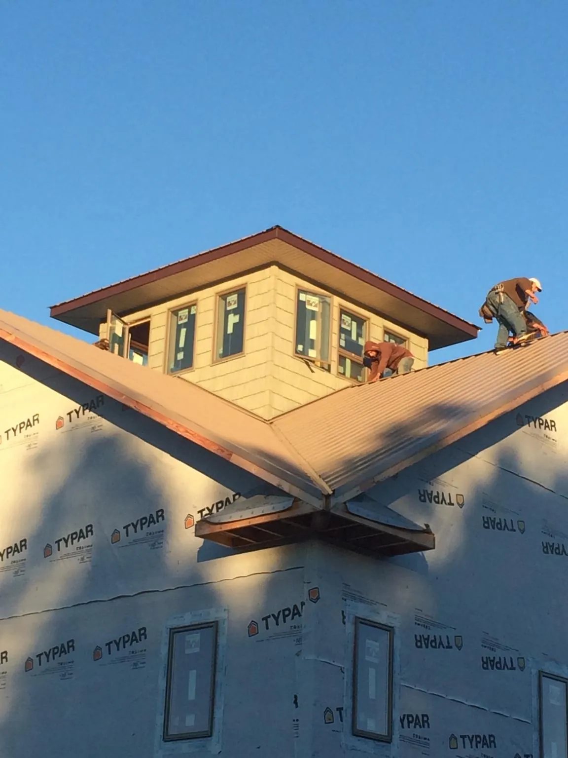 Roofers working around a rooftop cupola on a new metal roof at sunset — Roof Waterproofing in South Houston by Roofing Brothers
